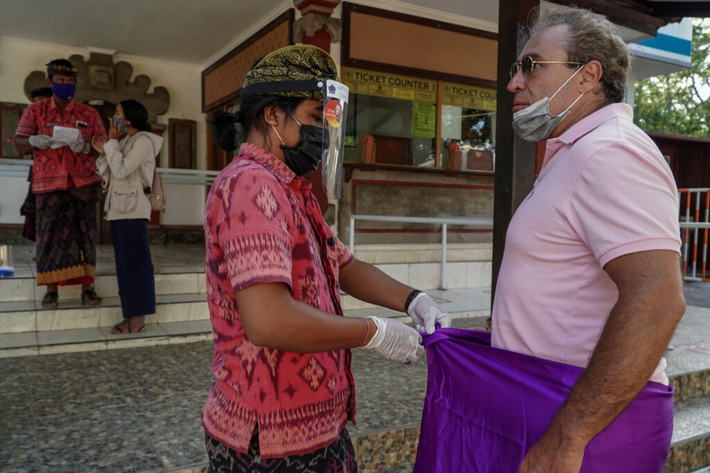 Petugas Memasangkan Sarung dan Pengikatnya di Uluwatu